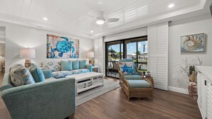 A spacious living room with a large window, a ceiling fan, and a view of the outdoors. - Newly Renovated Dock View 2 bed, 2 bath at Sanibel Moorings #1641 (Sanibel)
