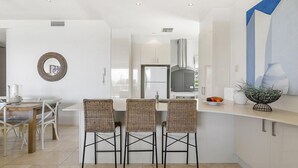 A modern kitchen with a central island, white cabinetry, and a built-in oven. - Relax in stylish comfort, Sunshine Beach (Sunshine Beach)
