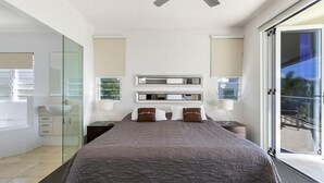 A modern bedroom with a large bed, a ceiling fan, and a glass shower enclosure. - Relax in stylish comfort, Sunshine Beach (Sunshine Beach)