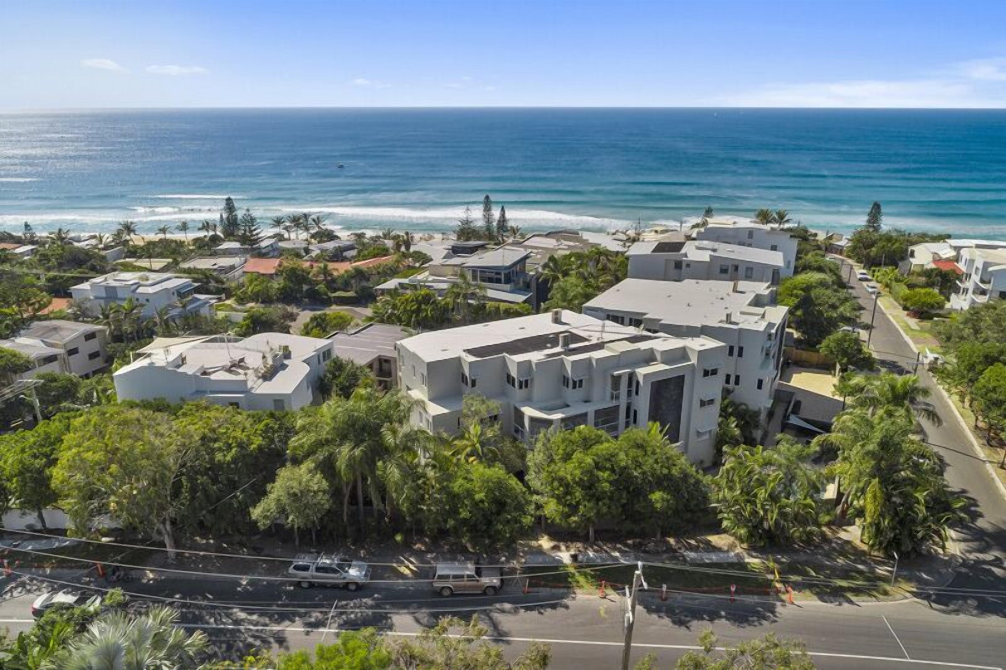Una zona residencial costera con edificios modernos, una carretera y vista al océano.