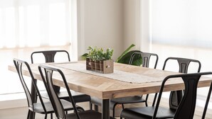 A dining table with six black chairs, a wooden table, and a plant in a wooden crate.