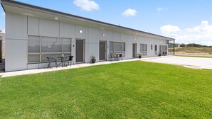 A modern building with a flat roof, large windows, and a well-maintained lawn.