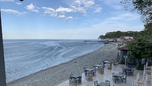 En terrass vid havet med bord och stolar, med utsikt över oceanen.