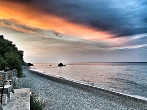 Une plage avec un sentier de pierres menant à un espace aménagé avec des tables et des chaises.
