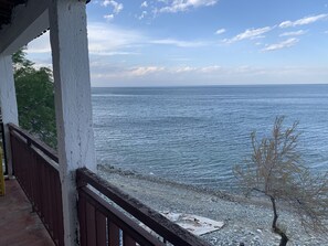 Une vue sur la mer depuis un balcon doté d’une balustrade, avec un rivage rocheux et un ciel dégagé.