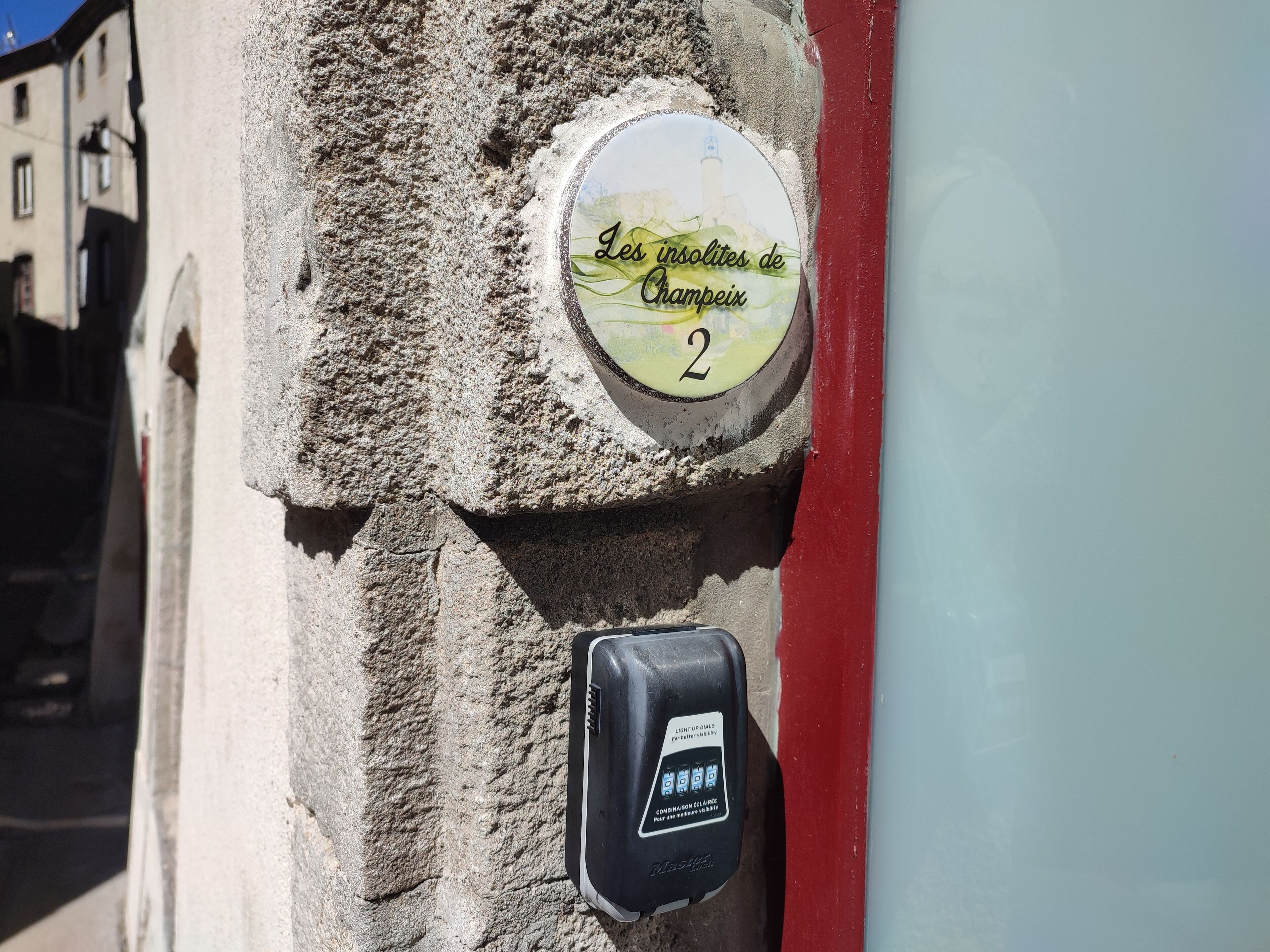 A stone wall with a sign indicating 'Les Solitudes de Champeix' and a parking meter.