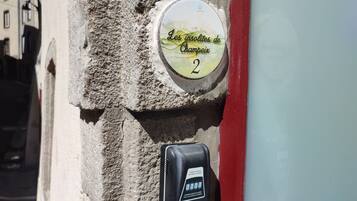 A stone wall with a sign indicating 'Les Solitudes de Champeix' and a parking meter.