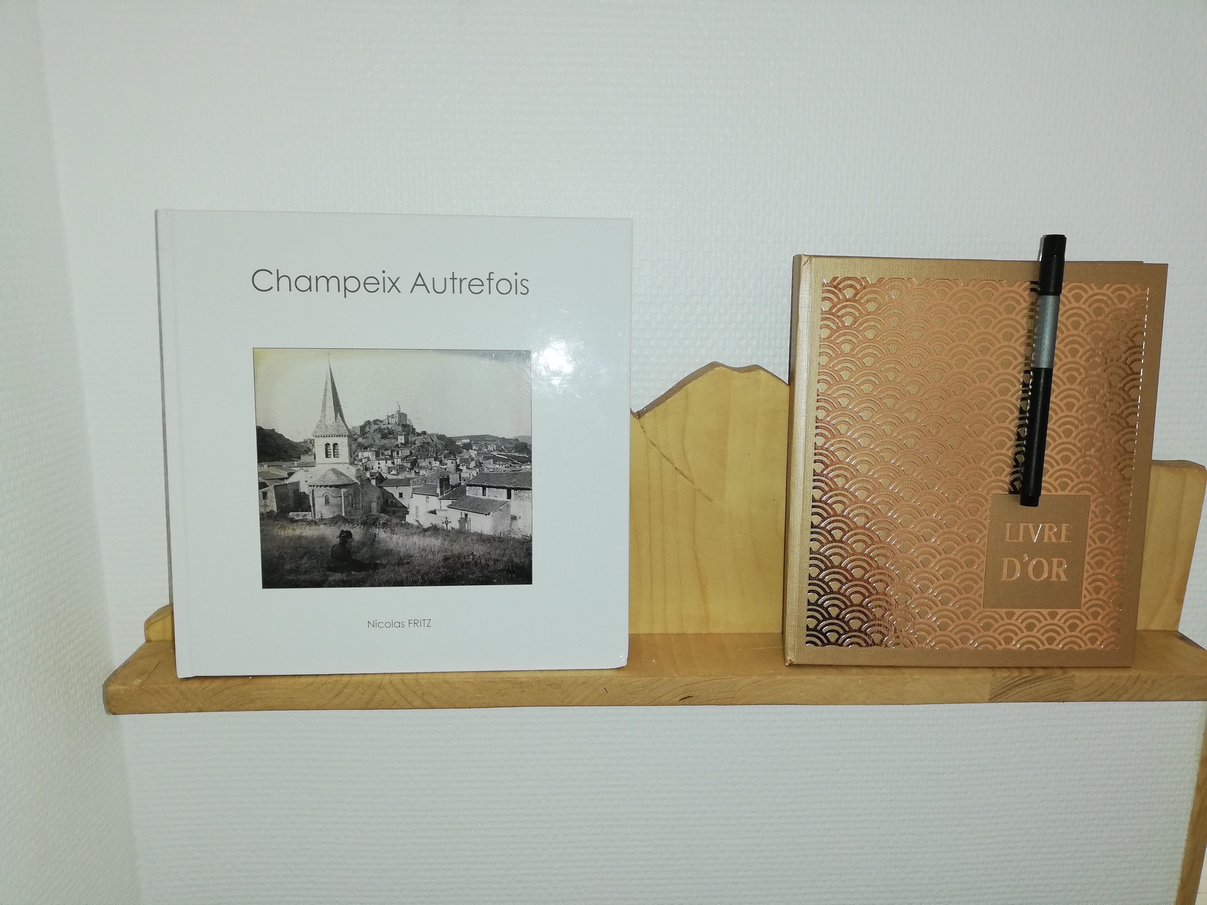 Kirja, jonka nimi on »Champeix Autrefois», ja jossa on mustavalkoinen valokuva kaupungista sekä kynä koristeellisessa rasiassa.