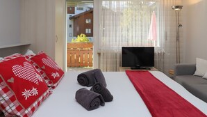 Une chambre d’hôtel équipée d’un lit, d’une télévision, d’un canapé et offrant une vue sur l’extérieur.