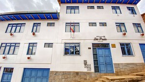 Un hotel con varias puertas y ventanas azules, un letrero que dice "Del Prado" y una bandera.