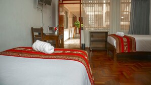 Habitación de hotel con dos camas, un escritorio, una silla, un televisor y un letrero que indica la salida.