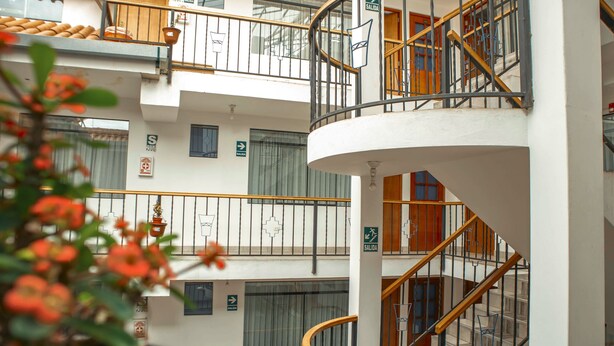 Un interior de varios niveles con una escalera caracol central, varios balcones y señalización.