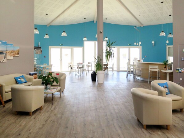 A spacious, well-lit interior with a high ceiling, white furniture, and a large potted plant.