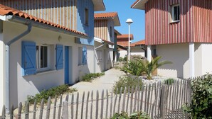 A row of traditional Mediterranean-style buildings with terracotta roofs, wooden shutters, and a narrow street. - Cosy apartment for 4 guests with WIFI, pool, TV, terrace and pets allowed (Biscarrosse)