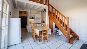 A modern kitchen with a dining area, a wooden staircase, and a white refrigerator. - Lovely apartment in villa for 6 people with WIFI, pool, TV, terrace and pets allowed (Biscarrosse)
