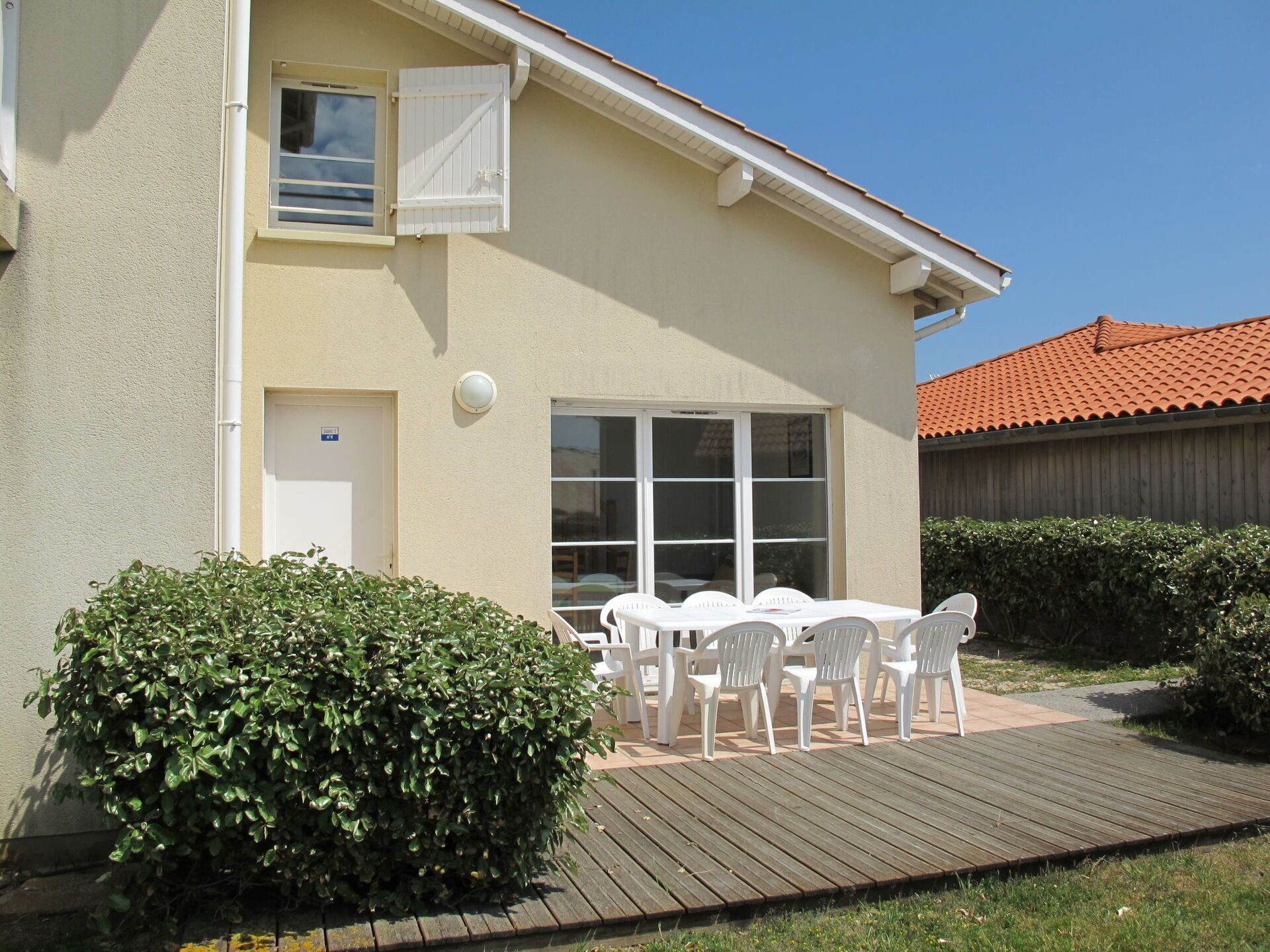 A two-story building with a patio area featuring a table and chairs.