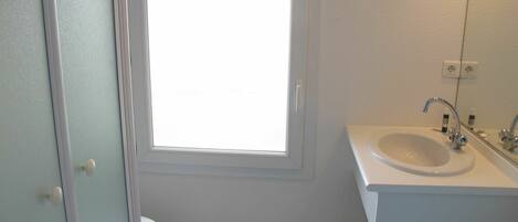 A small, clean bathroom with a toilet, sink, and window.