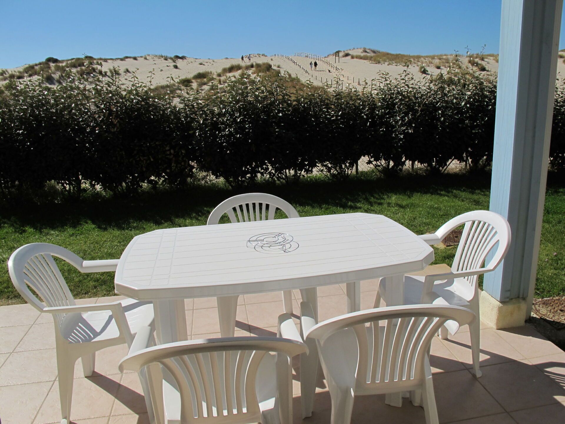 A covered outdoor dining area with a table and chairs, overlooking a vineyard.