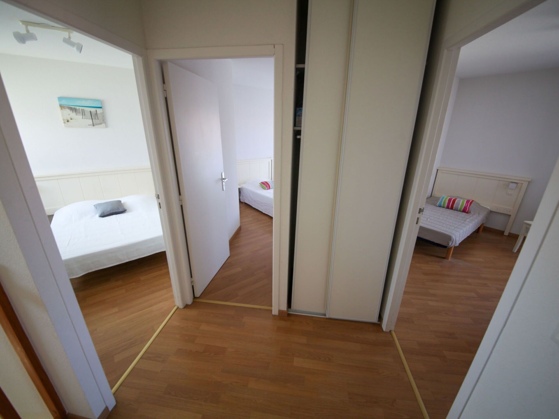Une chambre avec deux lits, un plancher en bois et des murs blancs.