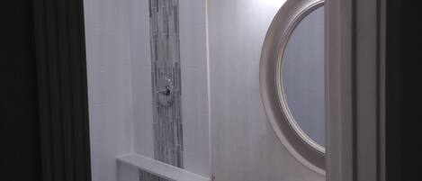 A bathroom with a shower, a sink, and a mirror.