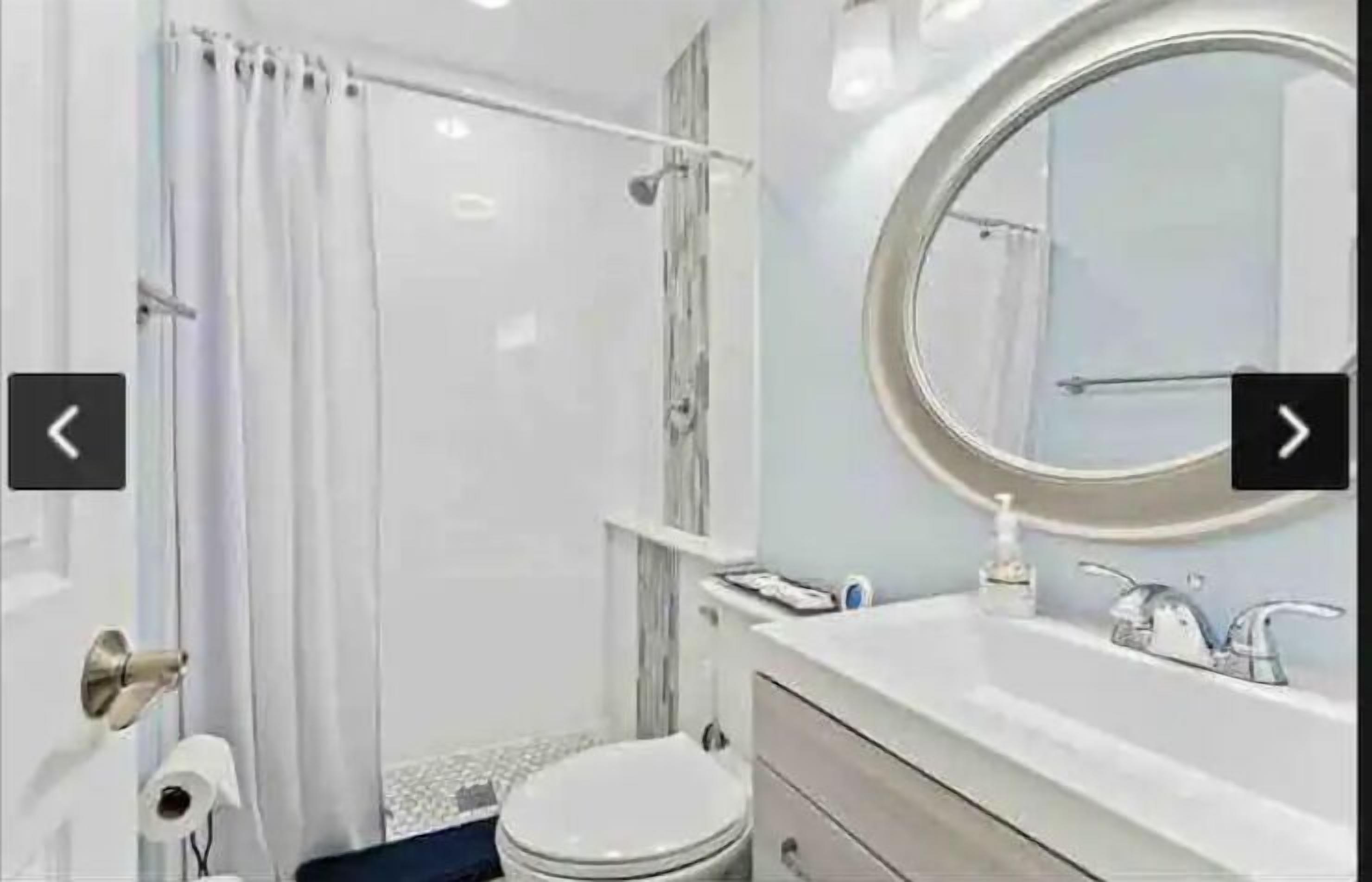 A modern bathroom with a shower, toilet, and sink.