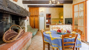 A rustic dining area with a stone fireplace, wooden furniture, and a view into the kitchen. - Wonderful private villa for 6 people with private pool, TV, patio and pets allowed (Moissac-bellevue)