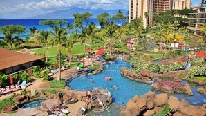 Un resort con una piscina grande, palmeras y vista al océano.