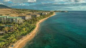 Un complejo turístico costero con propiedades frente a la playa, una playa de arena y una vista despejada del océano.