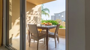 Ein Balkon mit Frühstückstisch, Korbstühlen und Blick auf Gebäude und Grünflächen.