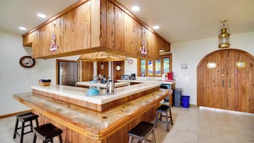 Eine Küche mit Holzausstattung, einer zentralen Kochinsel mit Barhocker, einem Kühlschrank und einem Herd.