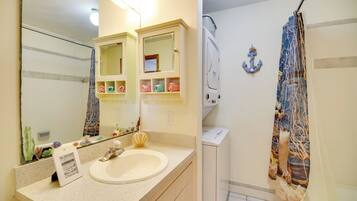 A bathroom with a sink, mirror, towel rack, and shower curtain.