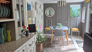 Uma cozinha com mesa de jantar, cadeiras, uma planta em vaso e um quadro negro.