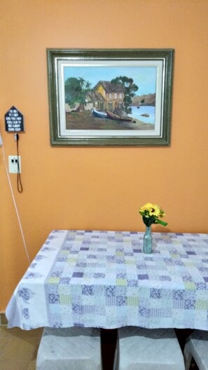 Una habitación con una mesa cubierta por un mantel a cuadros, un cuadro enmarcado en la pared y un jarrón con flores sobre la mesa.