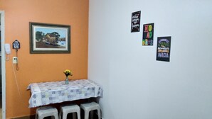 Een kamer met een oranje wand, een lijst met afbeelding, een tafel met een bloemstuk en drie decoraties aan de muur.
