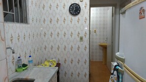A small bathroom with a sink, a toilet, and a wall-mounted clock. - Apartment in front of the beach Vl. Caiçara (Vila Caiçara)