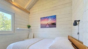 A bedroom with a wooden bed, a window, a wall-mounted shelf with a plant, and a sunset painting. - Beautiful private villa for 4 people with WIFI, A/C, TV and terrace (Zadar)
