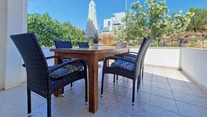An outdoor dining area with a wooden table and four wicker chairs, a white umbrella, and a view of buildings and trees. - Beautiful private villa for 4 people with WIFI, A/C, TV and terrace (Zadar)
