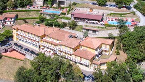A hotel with multiple floors, outdoor swimming pools, and a parking area.