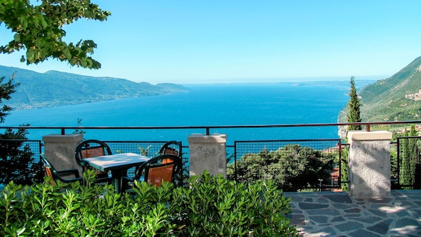 A terrace with a table and chairs overlooking a coastal view.