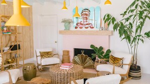 A cozy living room with a fireplace, wooden furniture, and hanging yellow pendant lights. - Les Cactus (Palm Springs)