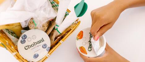 Una mano sosteniendo un envase de yogur Chobani.