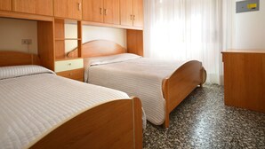 A hotel room with two wooden beds, a wooden wardrobe, a small desk, and a window with sheer curtains. - Nice apartment for 6 people with A/C, TV, terrace and pets allowed (San Michele Al Tagliamento)