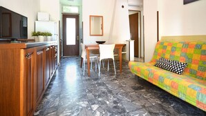 A modern kitchen with a TV, cabinets, and a dining area with a table and chairs. - Nice apartment for 6 people with A/C, TV, terrace and pets allowed (San Michele Al Tagliamento)
