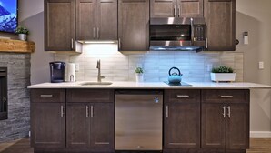 A modern kitchen with dark wood cabinets, stainless steel appliances, and a built-in dishwasher.