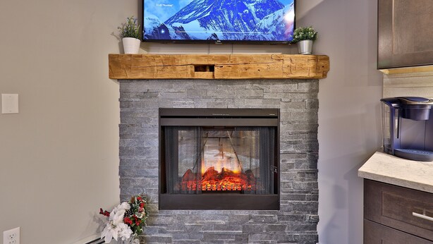 A fireplace with a TV above it displaying 'Kingdoms of the Sky'.