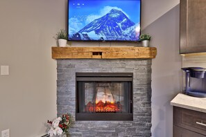 Una chimenea de piedra con un televisor sobre ella mostrando un paisaje de montaña.