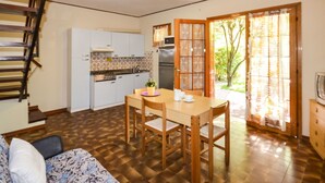 Una cocina compacta con armarios blancos, una mesa de comedor de madera y un horno empotrado.