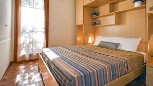 Un dormitorio con cama, armario de madera y ventana con cortinas.