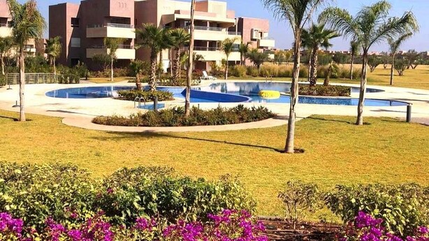 A hotel with a swimming pool, palm trees, and a well-maintained lawn. - Apartment Marrakech Prestigia Golf City 4601 (Marrakech)