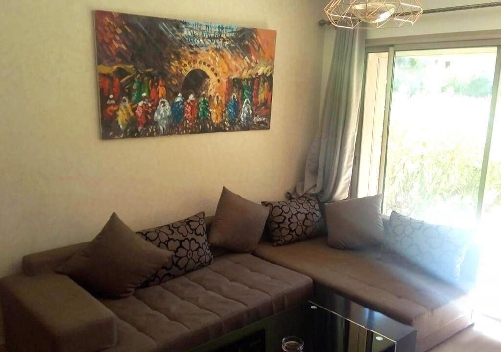 Een woonkamer met een hoekbank, een schilderij aan de muur en een raam met gordijnen.